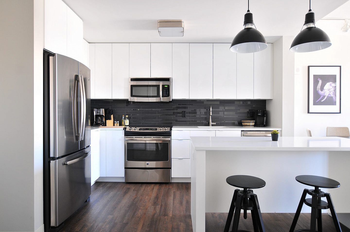 a kitchen with white cabinets and black tile