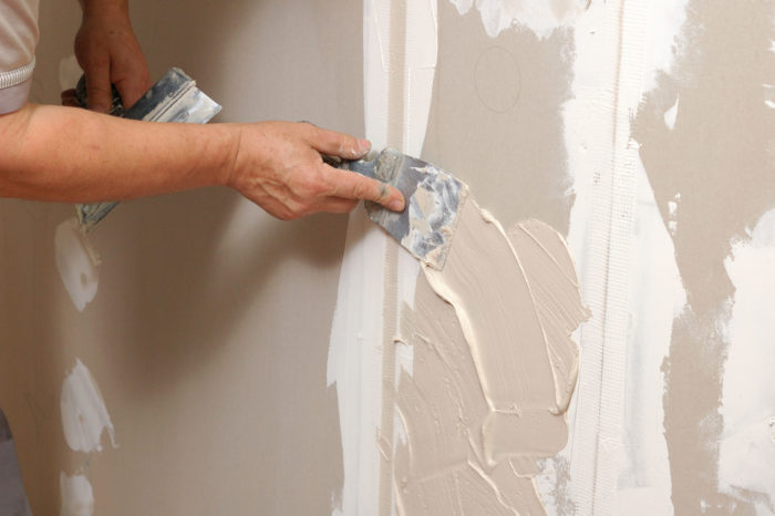 a person using a spatula to put plaster on a wall