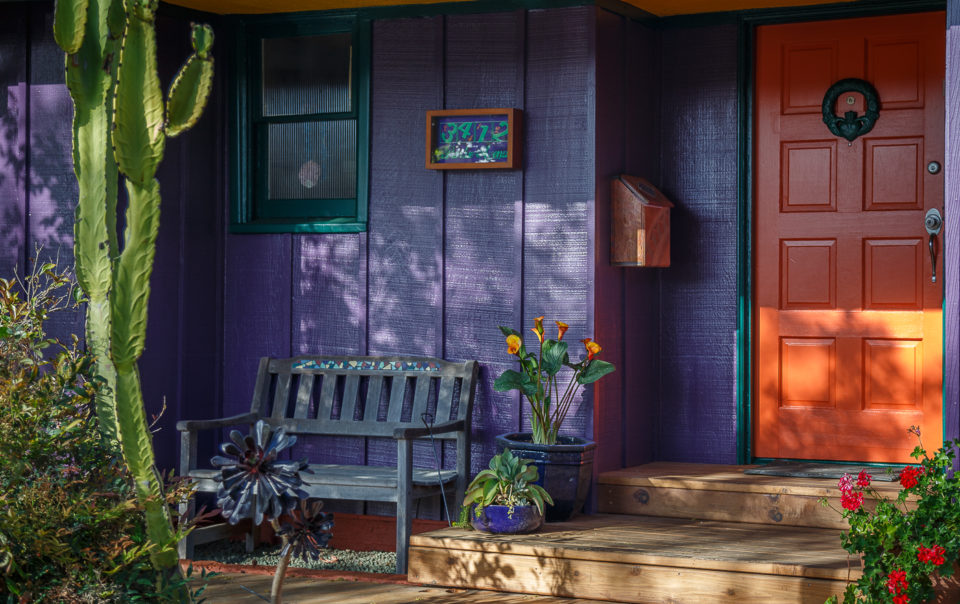 a purple house with a bench and potted plants