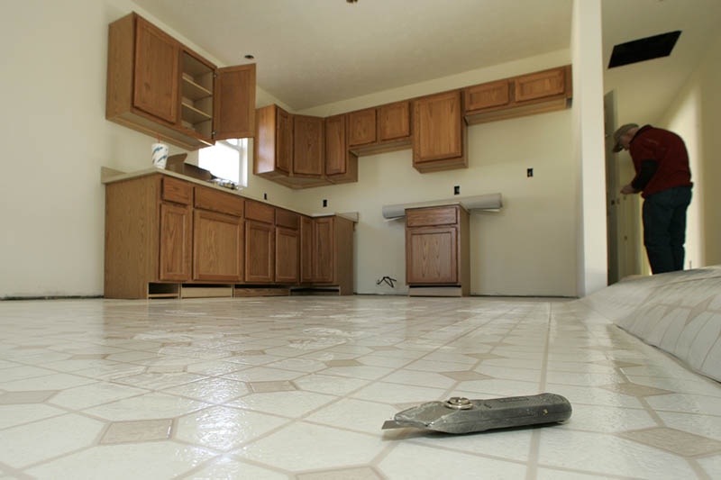 a room having tiled floor, wooden kitchen setup and a man