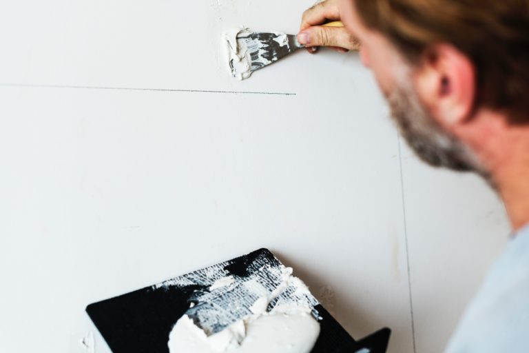 a person using a spatula to put a line on a wall