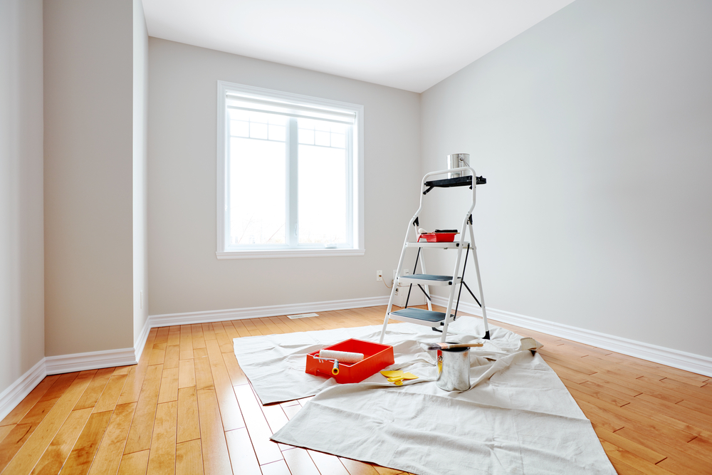 A room with a ladder and paint on the floor.