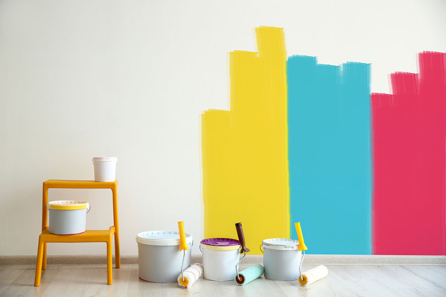 A room with colorful paint on the wall and a stool.